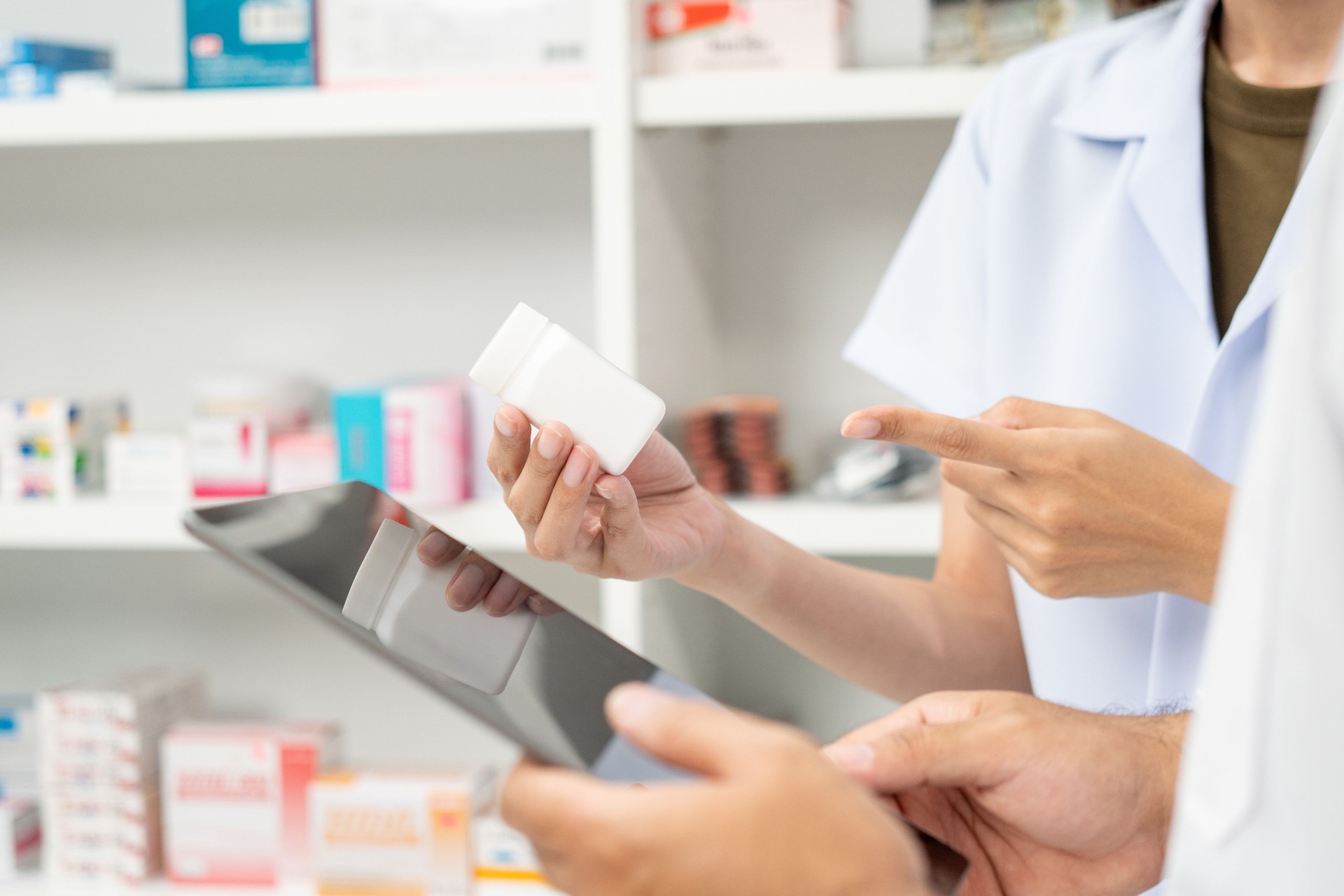 Two asian man and woman professional Pharmacist colleagues working at drugstore pharmacy. Asking the questions of medication standing near pharmacy shelves counter with medicines